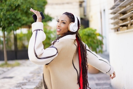 A Joyful Woman Wearing Headphones Dancing Happily in an Outdoor Urban Environment A Joyful Woman Wearing Headphones Dancing Happily in an Outdoor Urban Environment