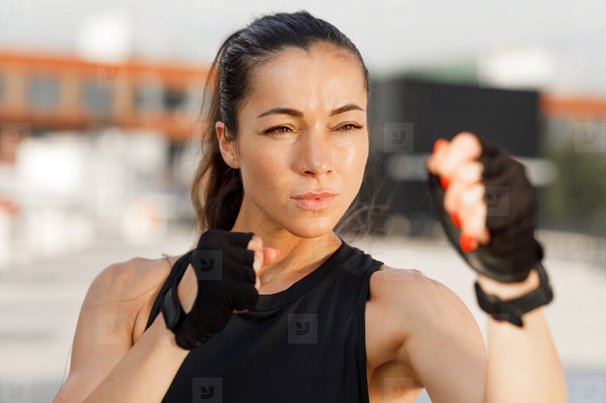 High detailed portrait of a young female standing in a battle pose  preparing for shadow boxing outdoors