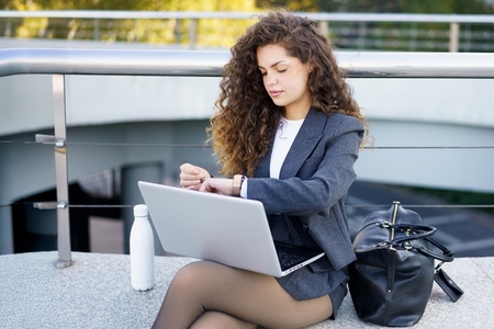 A young businesswoman works outdoors with her laptop  showcasing professionalism and drive