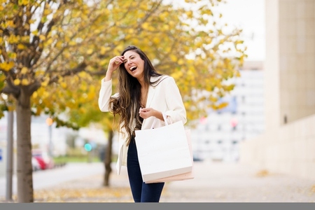 A Joyful Young Woman Enjoying a Day of Shopping in a Beautiful Autumn Park Setting A Joyful Young Woman Enjoying a Day of Shopping in a Beautiful Autumn Park Setting