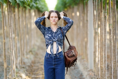 A young woman wearing a floral top paired with denim jeans is situated in a serene natural setting A young woman wearing a floral top paired with denim jeans is situated in a serene natural setting