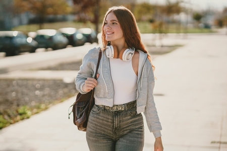 A young woman walks outdoors in headphones wearing a stylish outfit that shows her fashion A young woman walks outdoors in headphones wearing a stylish outfit that shows her fashion