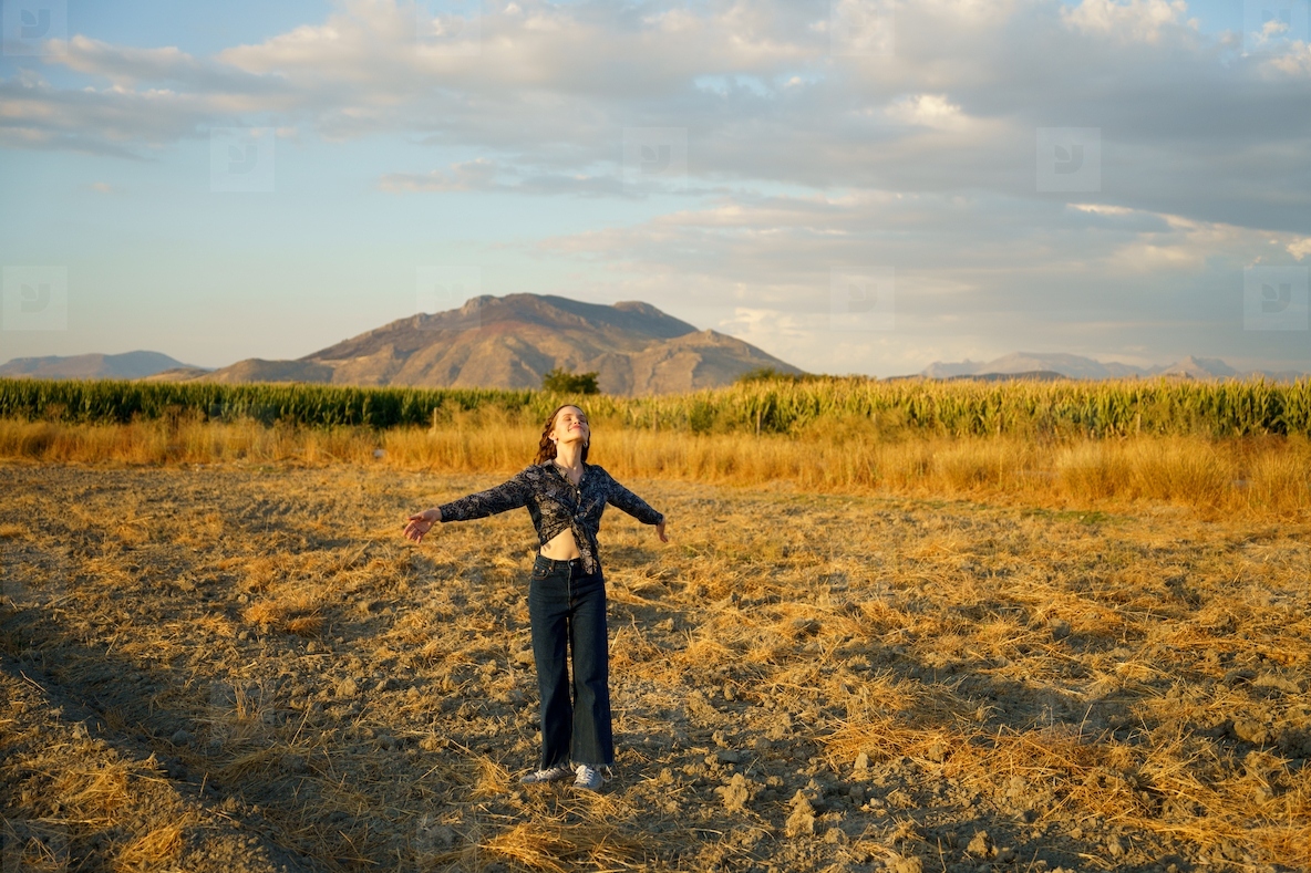 Embracing Nature Young Woman Standing in Open Field Surrounded by Majestic Mountains in Background
