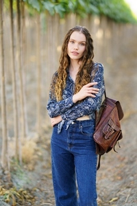 A Stylish Young Woman Wearing Denim and a Floral Top Posing Confidently in a Natural Setting A Stylish Young Woman Wearing Denim and a Floral Top Posing Confidently in a Natural Setting