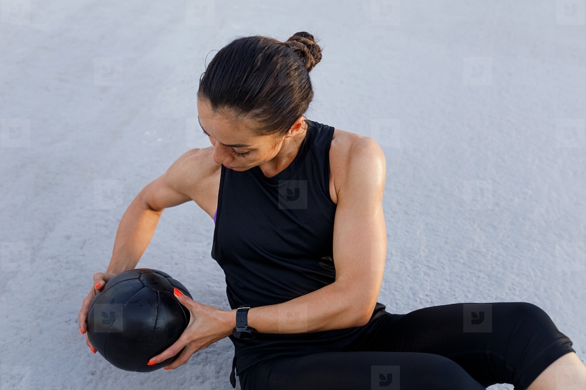 High angle view of a slim strong woman doing exercises with a medicine ball outdoors