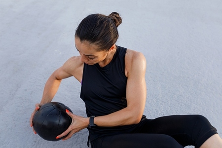 High angle view of a slim  strong woman doing exercises with a medicine ball outdoors