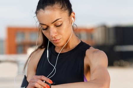 High detailed portrait of a young woman checking her swatches during a workout while standing on the roof