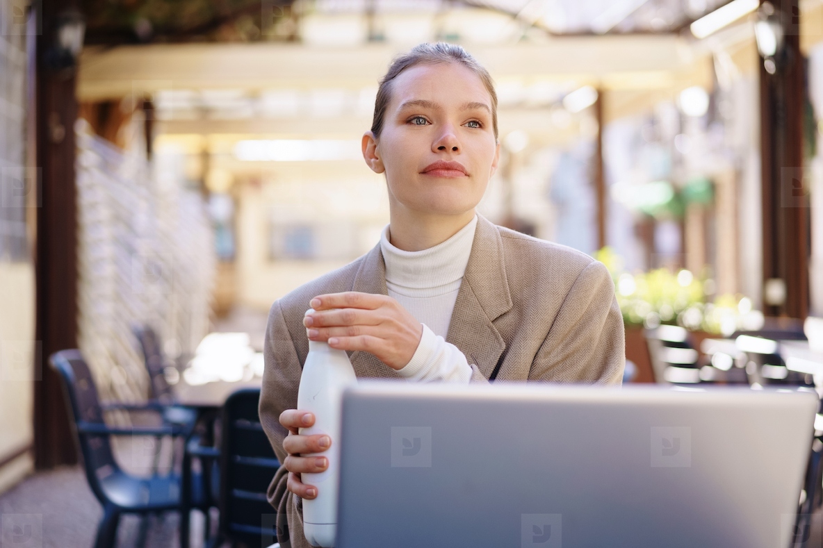 A thoughtful young professional sits in a cafe with their laptop  immersed in work and reflection