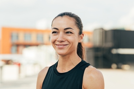 Portrait of a young cheerful female athlete standing on the roof