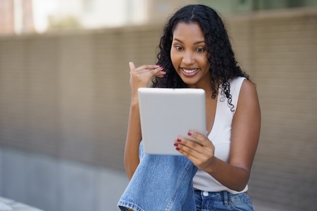 A Young Woman is Actively Engaged in a Video Call Outdoors Using Her Tablet Device A Young Woman is Actively Engaged in a Video Call Outdoors Using Her Tablet Device