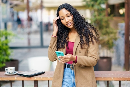 Young Woman Engaged with Smartphone in a Caf Setting Young Woman Engaged with Smartphone in a Caf Setting