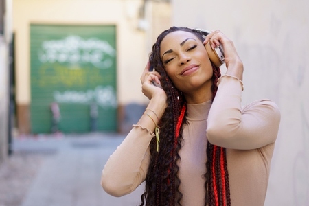 A joyful woman is fully enjoying her music amidst a lively urban setting filled with energy A joyful woman is fully enjoying her music amidst a lively urban setting filled with energy