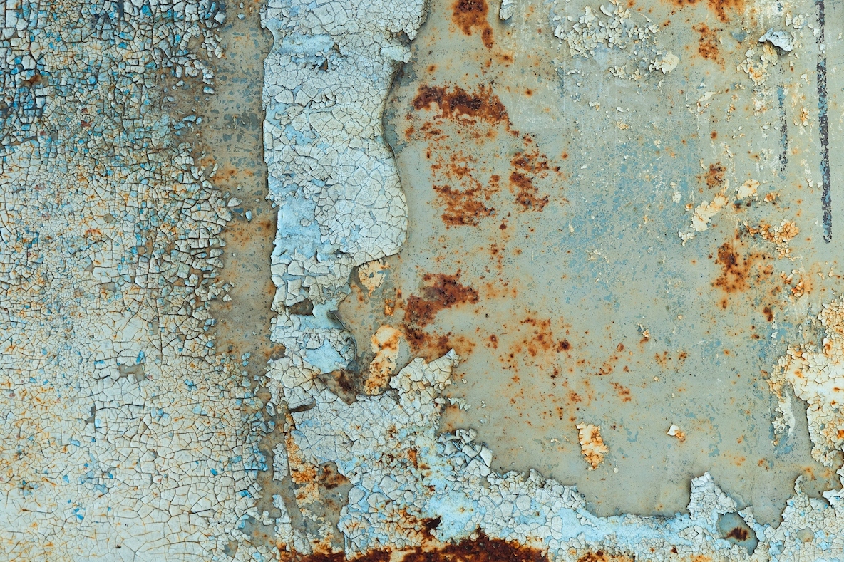 Close up of cracked peeling paint and rust on an old metal surface  creating a grunge abstract texture with weathered details