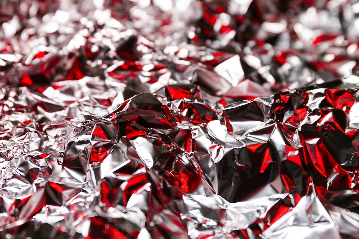 Shiny crumpled foil with silver and red reflections creating a metallic abstract design Futuristic texture with chrome surface and cyberpunk background style