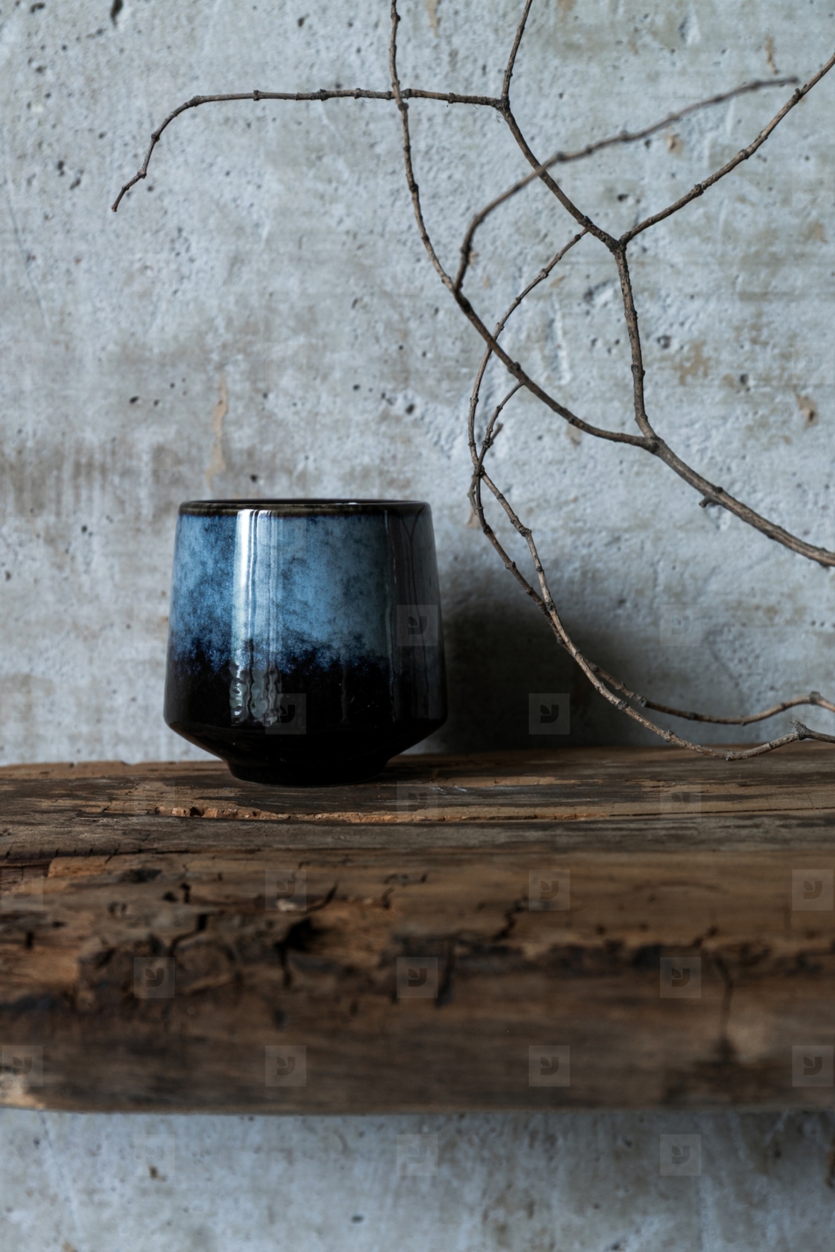 Dark ceramic cup on rustic wood with dry branch against concrete wall  minimal wabi sabi still life with natural textures