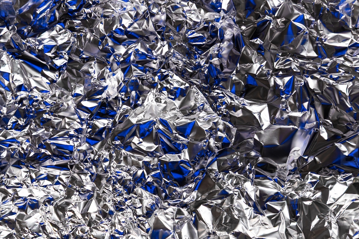 Shiny crumpled silver foil with blue reflections  metallic texture background with abstract shapes and light play