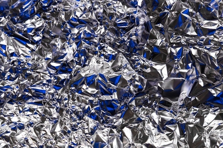 Shiny crumpled silver foil with blue reflections  metallic texture background with abstract shapes and light play