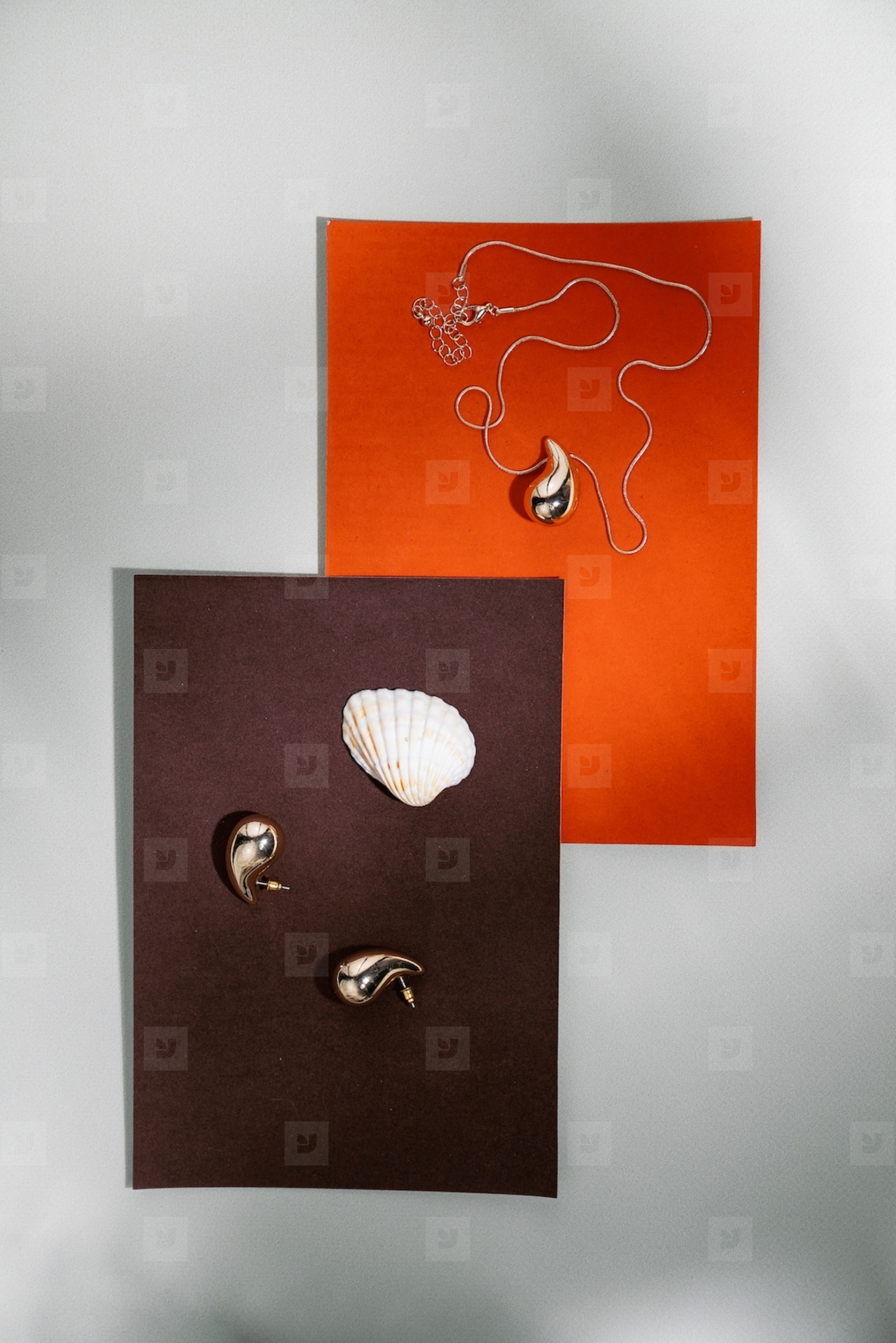 Stylish jewelry composition with golden necklace  earrings and seashell on orange and brown paper background in minimal design