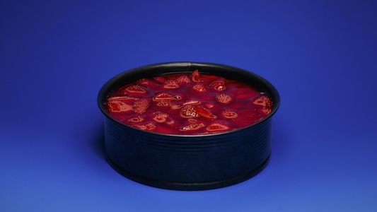 Still life of strawberry cake in round tin against blue background
