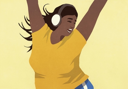 Carefree young woman with headphones listening to music and dancing with arms raised