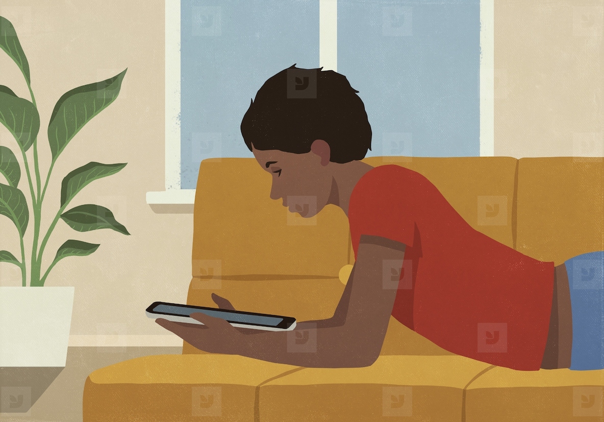 Boy relaxing at home laying on sofa and using digital tablet