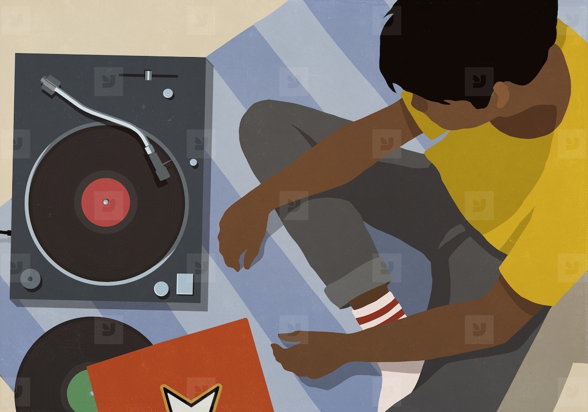 High angle view of young man listening to music at record player