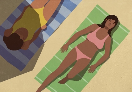 Young women sunbathing on towels on sunny summer beach