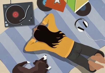 View from above of young woman listening to music with dog