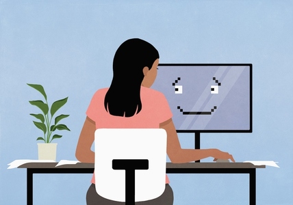Woman working at computer with smiley face on screen