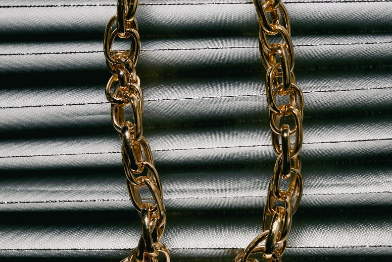 Golden chain necklace on metallic fabric background, luxury accessory with elegant texture and stylish modern composition.