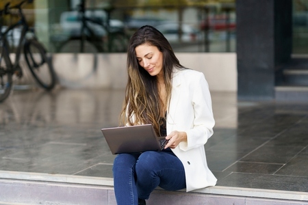 A young woman uses her laptop outdoors in a lively urban area  blending work and relaxation