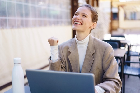 A Joyful Businesswoman is Celebrating Her Success at a Laptop While Outdoors in Nature
