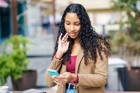 A young woman enjoys the outdoors while engaged with her smartphone  creating a cheerful vibe