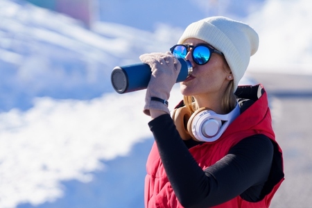 Athletic woman in warm clothes drinking water in nature Athletic woman in warm clothes drinking water in nature