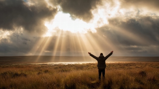 Person standing in wide open field with arms raised  embracing sunlight breaking through clouds  radiating joy and freedom