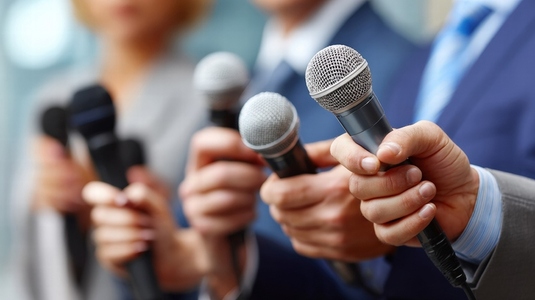 Journalists holding microphones during press conference  showcasing professional atmosphere and engagement with media