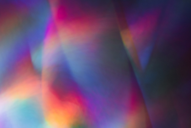 Soft colorful abstract background with blurred light reflections in purple, blue, and pink tones, creating a dreamy gradient texture.