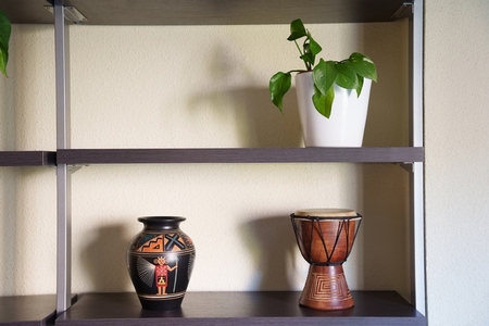 Decorative earthy scene  Minimalist display with warm natural lighting  Elegant arrangement of ceramics and wood with gentle light accentuating textured wall details