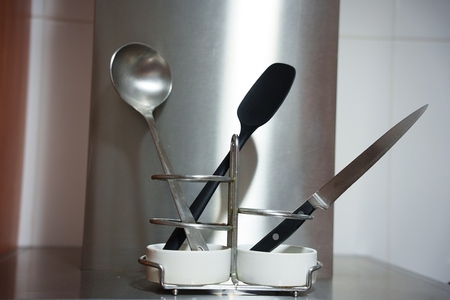 Modern kitchen organization  Contemporary stainless utensil display  Refined stainless steel stand featuring ladle and knife against polished modern kitchen backdrop