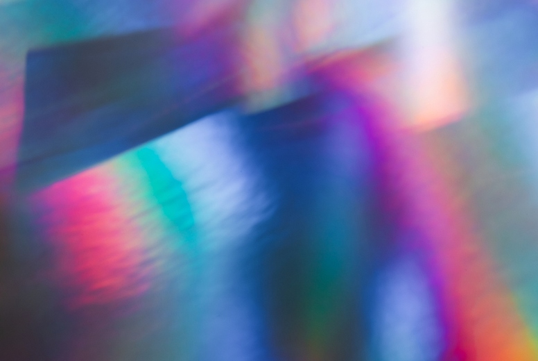 Soft colorful abstract background with blurred light reflections in purple, blue, and pink tones, creating a dreamy gradient texture.