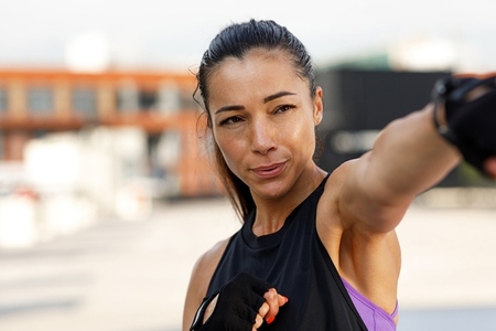 Portrait of young female boxer practicing punches outdoors  High detailed portrait of young female doing intense shadow punches outdoors