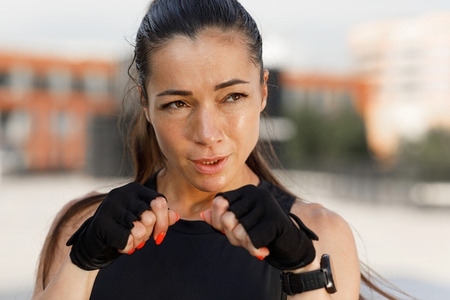 Close up portrait of young sportswoman in gloves ready for shadow boxing  standing in a fighting stance