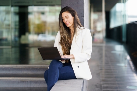 A young professional woman works on her laptop outdoors  highlighting her careerdriven mindset