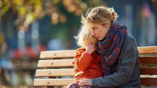 Mother comforting child park bench  emotional moment captured  warm autumn colors  candid scene  connection between parent