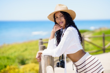 A Beautiful Young Woman Dressed in Summer Attire  Posing by the Beachside on a Sunny Day