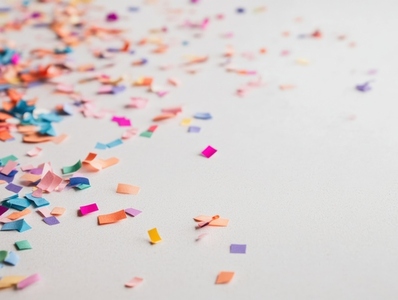 Colorful pieces of confetti scattered on light surface create festive atmosphere