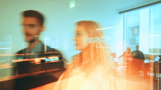 Professional man and woman walking in office showcasing collaboration and modern workspace Professional man and woman walking in office showcasing collaboration and modern workspace