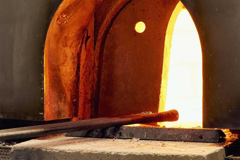 Tools in arched opening of hot glassblowing furnace