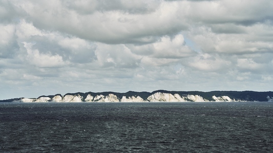 Scenic view of white cliffs of Denmarks coastline under fluffy Scenic view of white cliffs of Denmarks coastline under fluffy