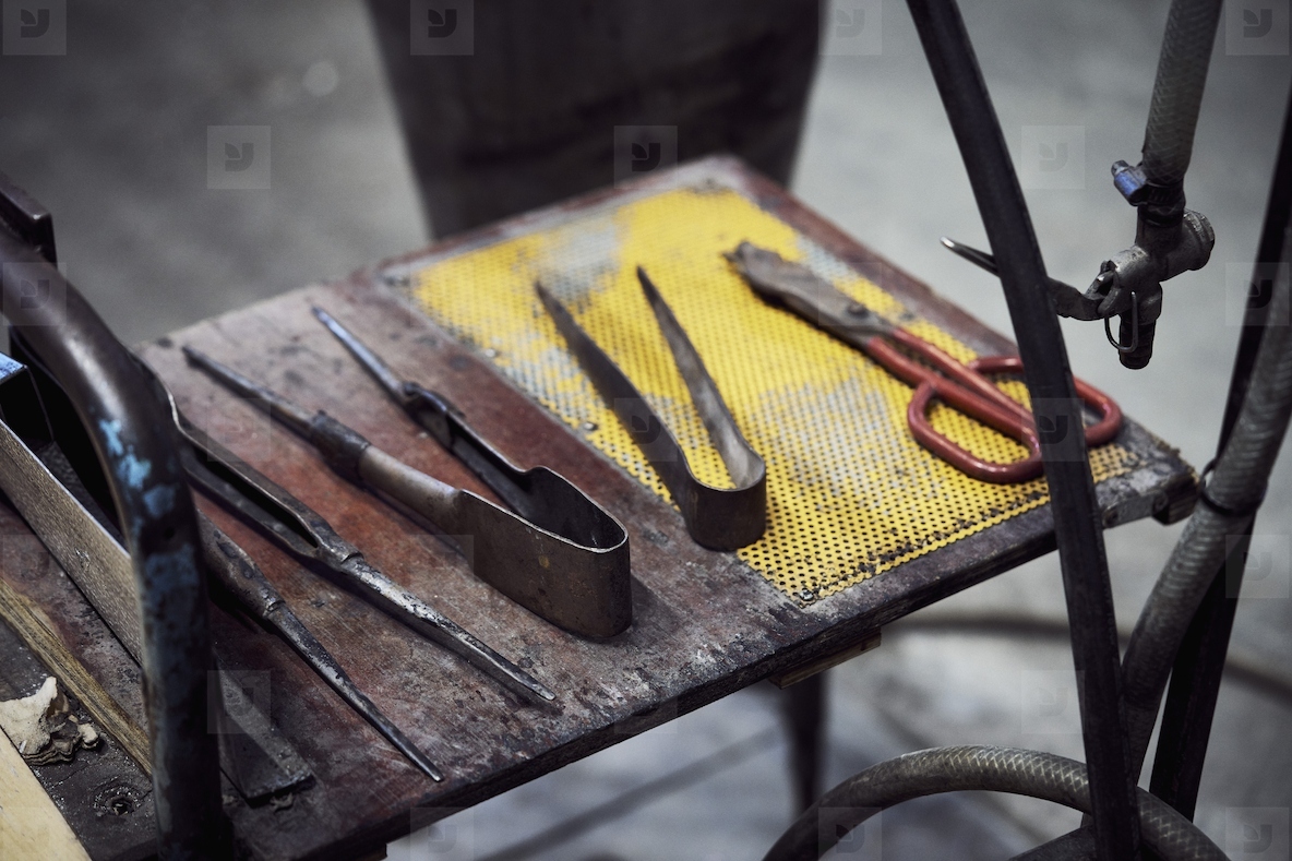 Glassblowing hand tools in a row on shelf in workshop